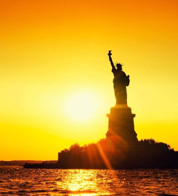 Frihetsgudinnen i New York i soloppgang.