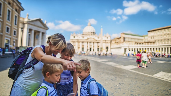 Turistfamilie besøker Roma og Vatikanet. De står på Piazza Papa Pio XII og sjekker veibeskrivelsen på smarttelefonen. Petersplassen og Peterskirken er synlig i bakgrunnen.