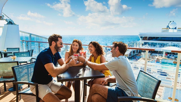 Voksene mennesker smiler og skåler på dekk på et cruiseskip