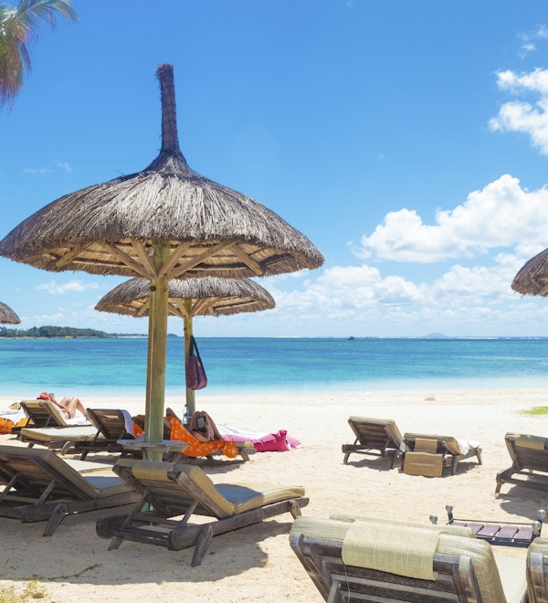 perfekt sted å hvile på stranden med halmparaplyer palmer og lange stoler