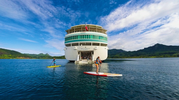Cruiseskip med mennesker på stand up paddle board i forkant