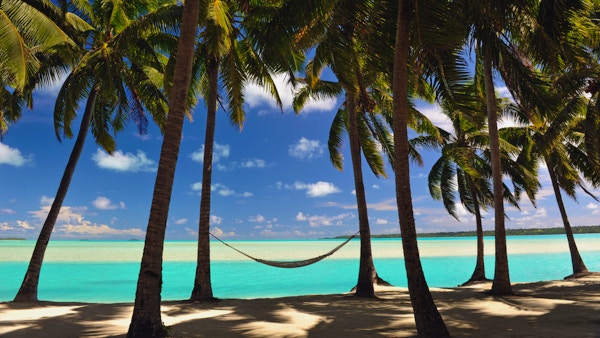 En hengekøye henger i skyggen av Coconut Palms ved siden av en rolig turkis lagune South Pacific