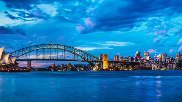 Solnedgang i Sydney med Harbour Bridge og operahuset i Sydney i bakgrunnen.