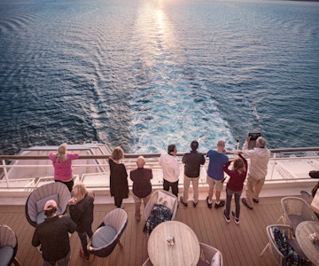 Mennesker står ved rekka pg ser på vakker utsikt fra cruiseskip