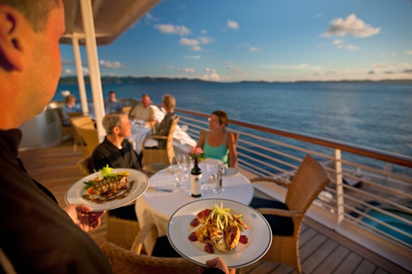 Kelner serverer mat på restaurant ute på dekk på yacht.