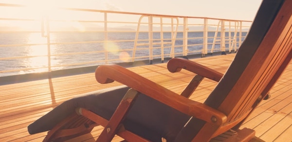 Solstol på skipsdekk med lag kveldssol og utsikt over havet.