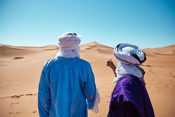 To mennesker står og ser ut over sanddyner