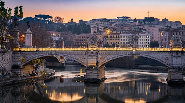 Lang eksponeringsbilde av elven tiber og en bro ved solnedgang i Roma, Italia