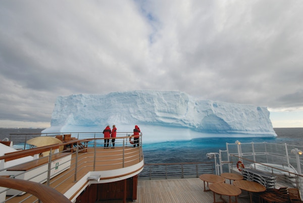 Gjester som observerer et isfjell fra dekk.