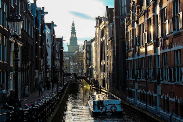 Kanalbåt i skyggen på en smal kanal i Amsterdam