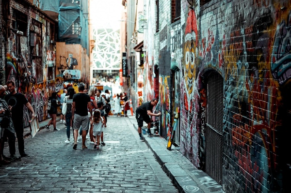 Mennesker som går i en gate med grafittigkunst på veggene