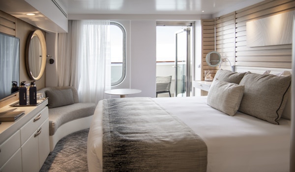 Seng, sofa og utgang til balkong i lugar på cruiseskip