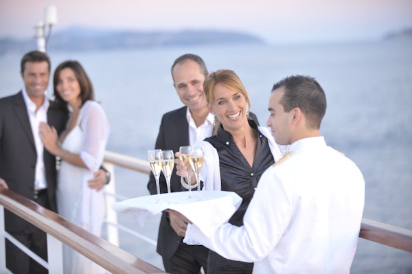 Servitør serverer champagne på dekk til smilende par