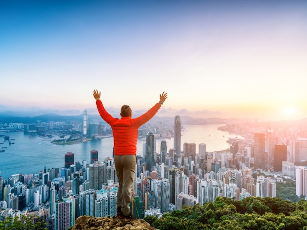 mann klatrer til fjelltopp, vendt mot Hong Kong skyline