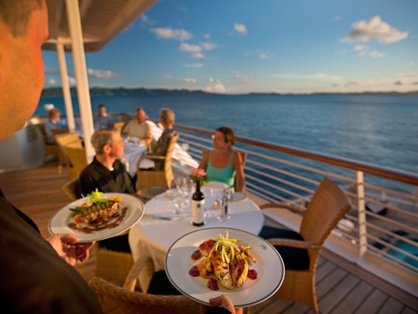 Kelner serverer mat på restaurant ute på dekk på yacht.