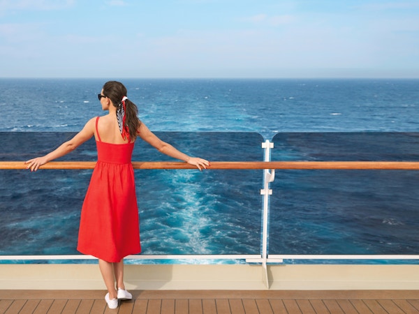 Kvinne i rød kjole ser ut mot horisonten