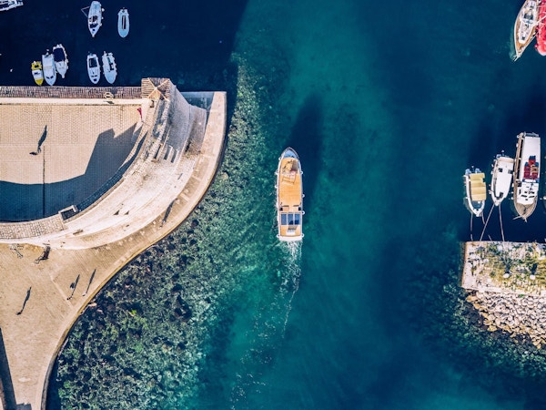 Ovenfra og ned utsikt over en båt som kommer inn i havnen i gamlebyen i Dubrovnik. Inngang ved sjøen i den gamle byen på Adriaterhavskysten.