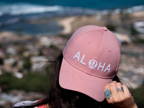 Kvinne i rosa caps med broderert Aloha