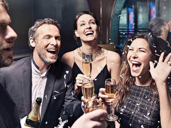 Mennesker feirer med champagne og smiler