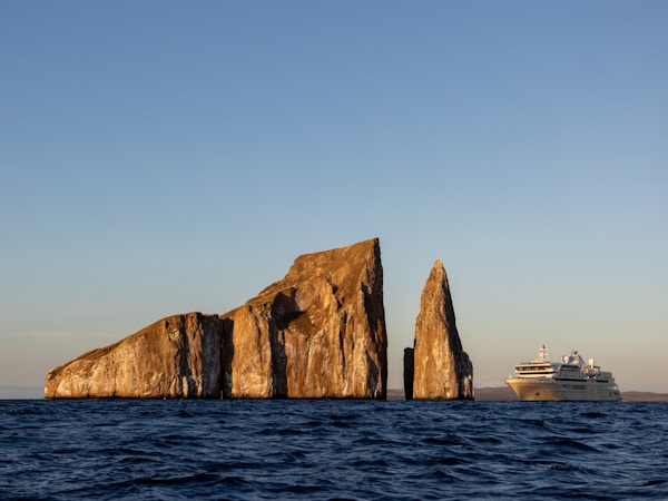 Silver Origin nærmer seg Kicker Rock ved solnedgang, Galapagosøyene.