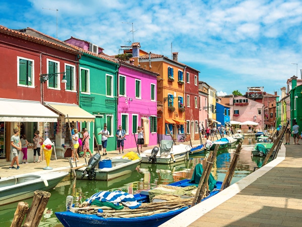 Fargerike hus på øya Burano i Venezia. Båter i kanalen.