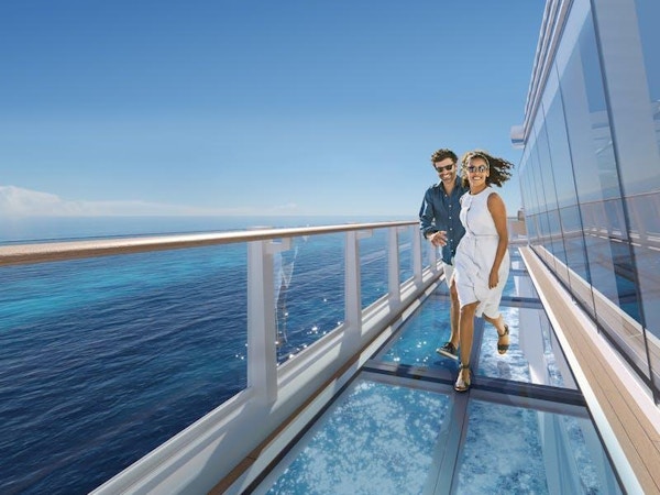 Par løper på glassbro på utsiden av cruiseskip.