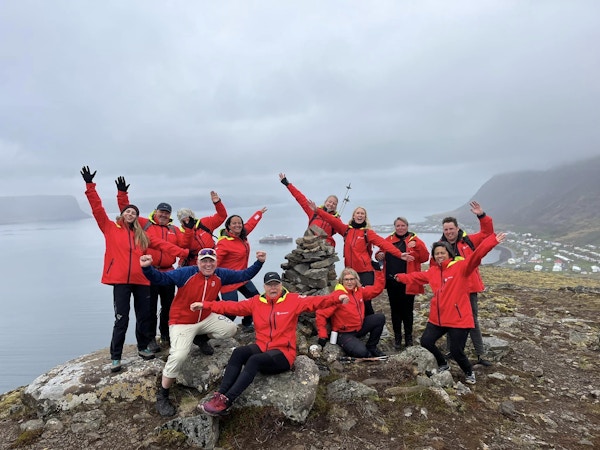 En gruppe mennesker i røde jakker på toppen av et fjell
