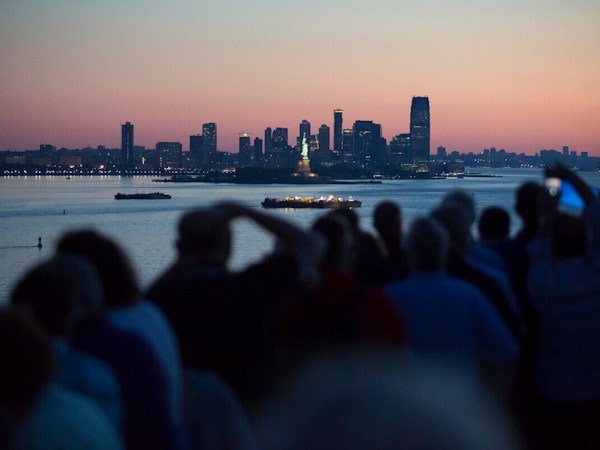 En gjeng mennesker ser på og tar bilde av Manhattan skyline