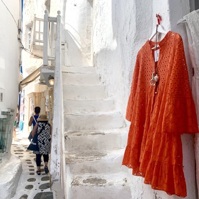 Orange kjole mot hvit vegg og trapp.