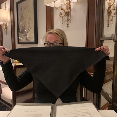 Dame holder opp svart serviett på restaurant.