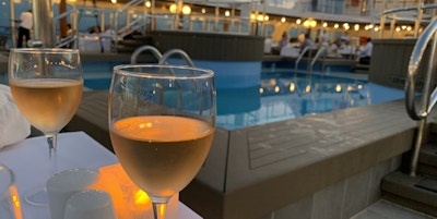 Et glass rosévin ved bassenget i skumringen.