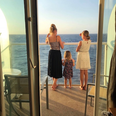 Mor og to døtre fotografert bakfra på balkong fra suite.