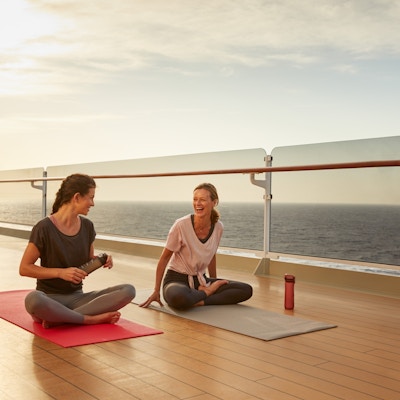 To kvinner på dekk på cruiseskip med yogamatte.
