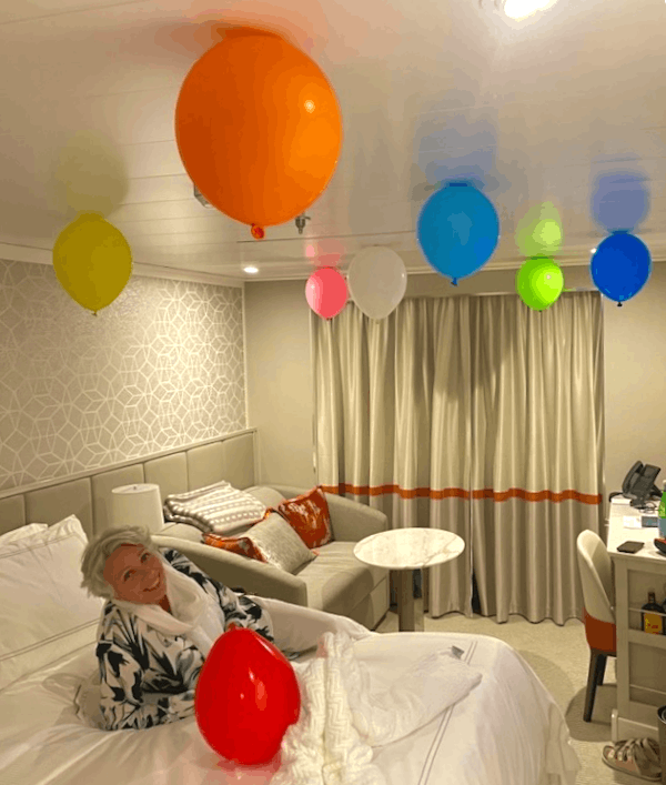 Kvinne ligger på en seng og i taket svever fargerike ballonger.