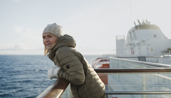 Kvinne står på dekk på cruiseskip og ser utover.