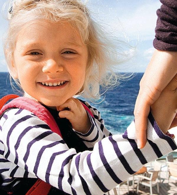 Jente holder hånda til en voksen på cruiseskip, har med sekk med bamse i.