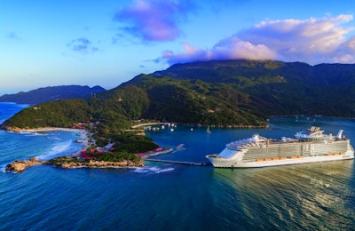 Stort cruiseskip ligger til kai ved en øy