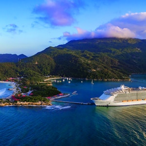 Stort cruiseskip ligger til kai ved en øy