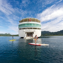 Cruiseskip med mennesker på stand up paddle board i forkant