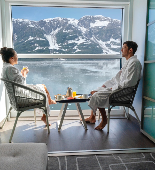 Par sitter på innglasset balkong og spiser frokost