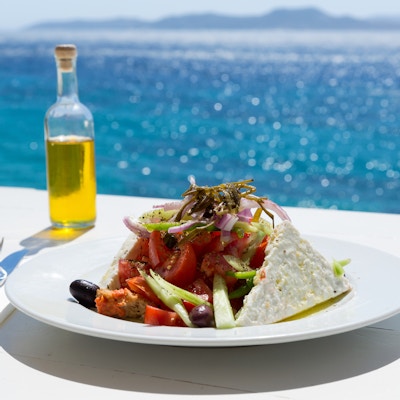 Gresk salat og olivenolje på solfylt havoppsett