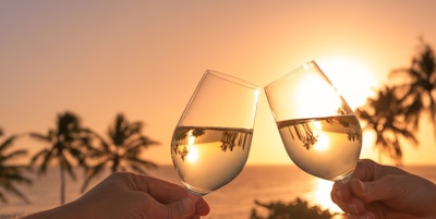 Skål med vinglass i en vakker solnedgang ved stranden.