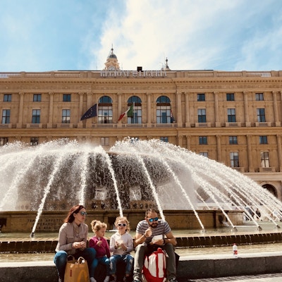 Genova familie som spisers is foran fontenen på Piazza de Ferrari